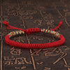 Red handwoven bracelet with multicolored King Kong knots on a textured background