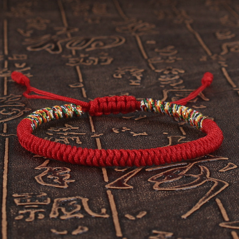 Red handwoven bracelet with multicolored King Kong knots on a textured background