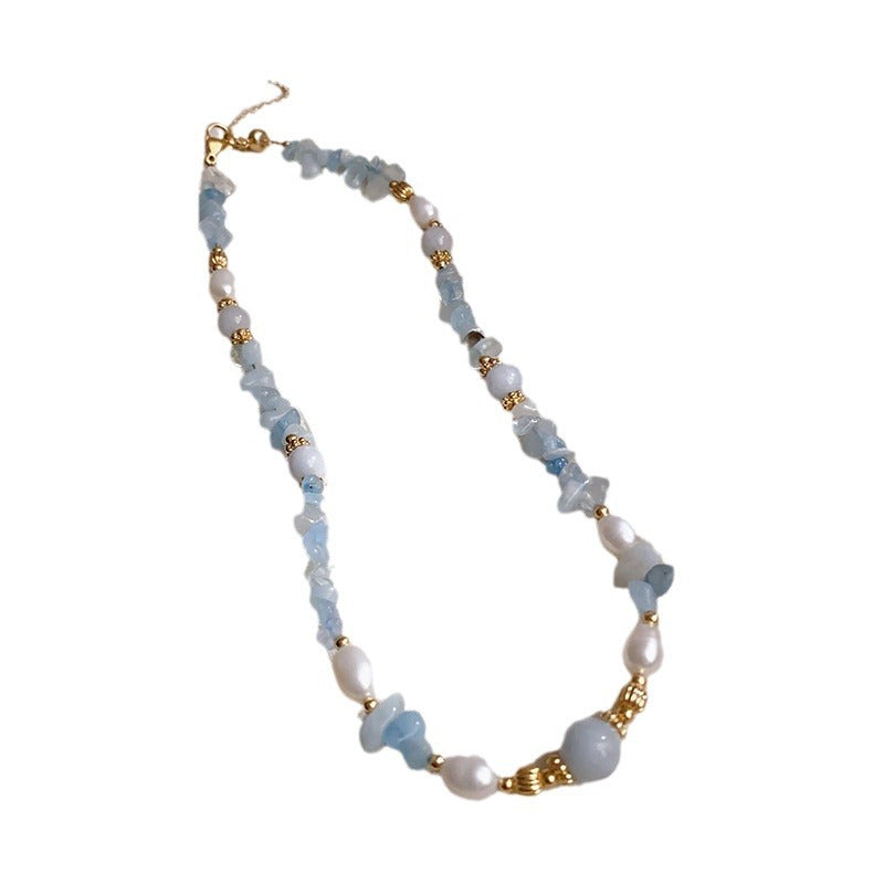 Blue aquamarine chip necklace with pearls on a textured surface