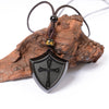 Black obsidian shield pendant necklace resting on wood
