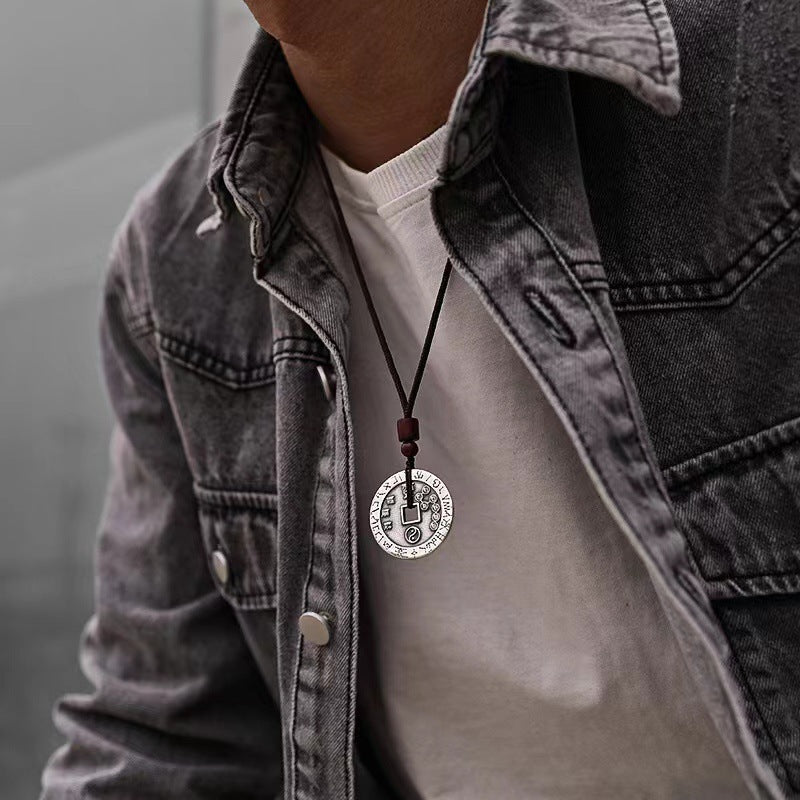 Man wearing a vintage silver-tone copper coin pendant on a black cord.