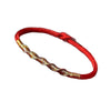Close up of a red braided bracelet with a gold twist detail on a wrist