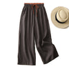 Dark brown wide leg cotton pants with an orange drawstring waist displayed next to a straw hat