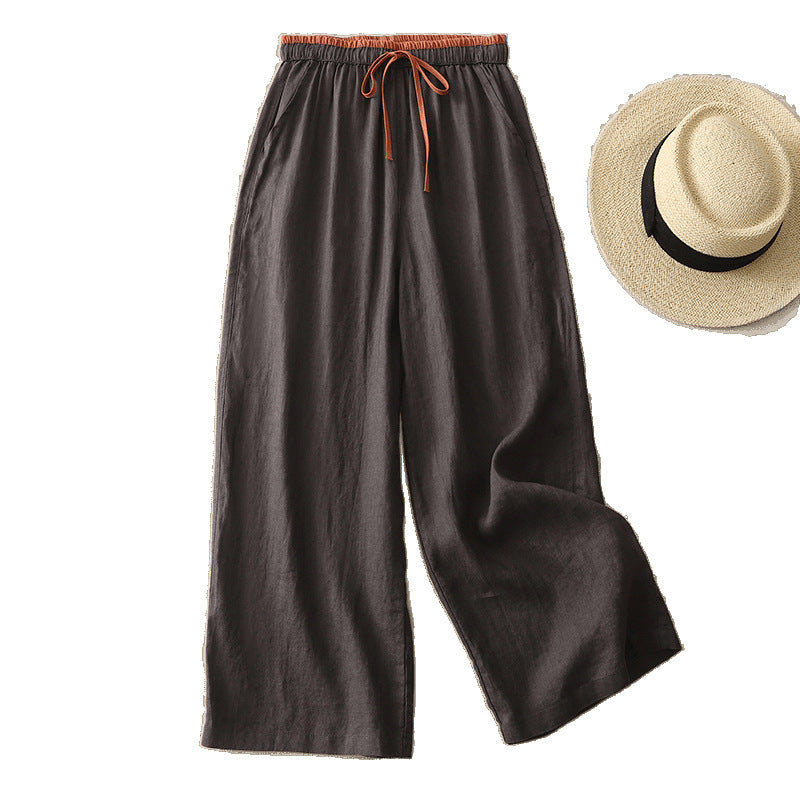 Dark brown wide leg cotton pants with an orange drawstring waist displayed next to a straw hat