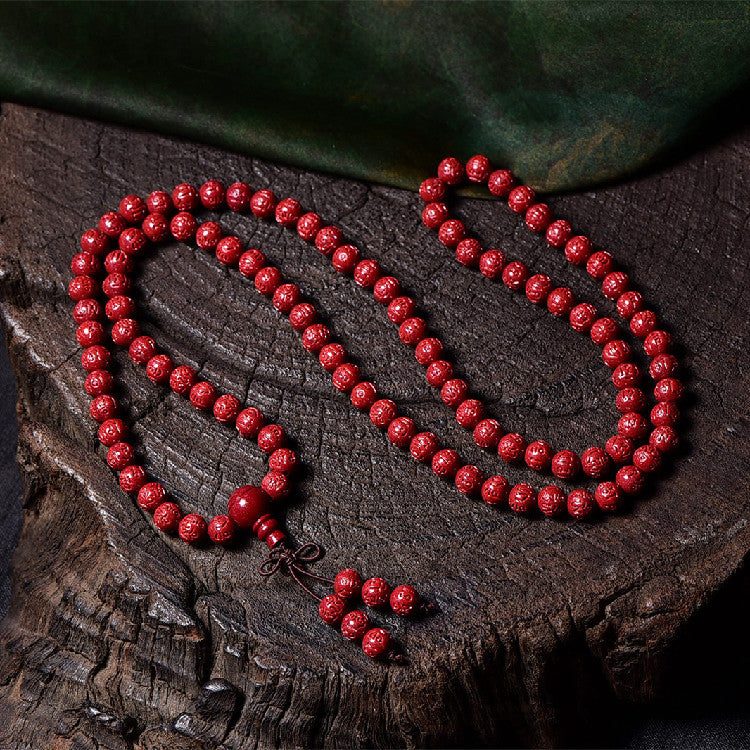 A wrist wearing a multi-wrap red cinnabar mala bracelet with a knotted tassel