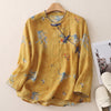 Front view of a yellow long sleeve linen top with blue floral patterns and knotted buttons