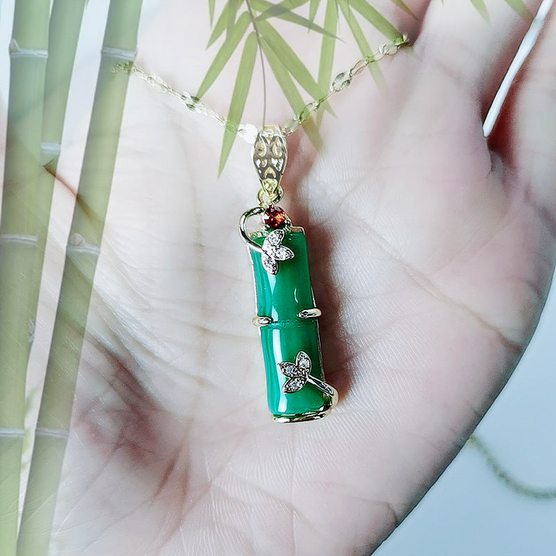 Gold-tone necklace with a green bamboo pendant held in hand