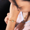 Close up of gold tone necklace with white jade pendant featuring blue and green enamel koi design