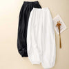 Black and white women's harem pants laid flat on a beige background