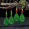 Green carved jade drop earrings hanging from a branch