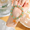 Wrist wearing a green bamboo bead bracelet with an orange lotus pod charm