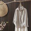 Apricot and black striped long sleeve shirts hanging on wooden hangers against a dark wood wall.