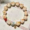 Close-up of a white bodhi seed bracelet with cat paw shaped beads and a gold charm.