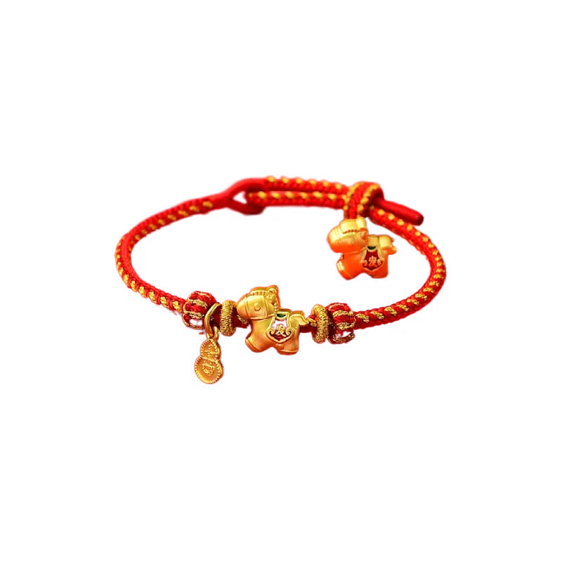 Close-up of a red braided cord bracelet with gold horse charms on a white background