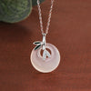 Close up of a sterling silver necklace with a round white chalcedony pendant and green bamboo leaves