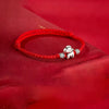 Close-up of a braided red cord bracelet with a silver horse charm on a red background