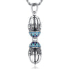 Silver-tone copper vajra pendant with blue enamel details on a wooden surface