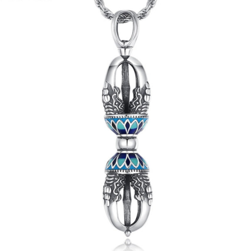 Silver-tone copper vajra pendant with blue enamel details on a wooden surface