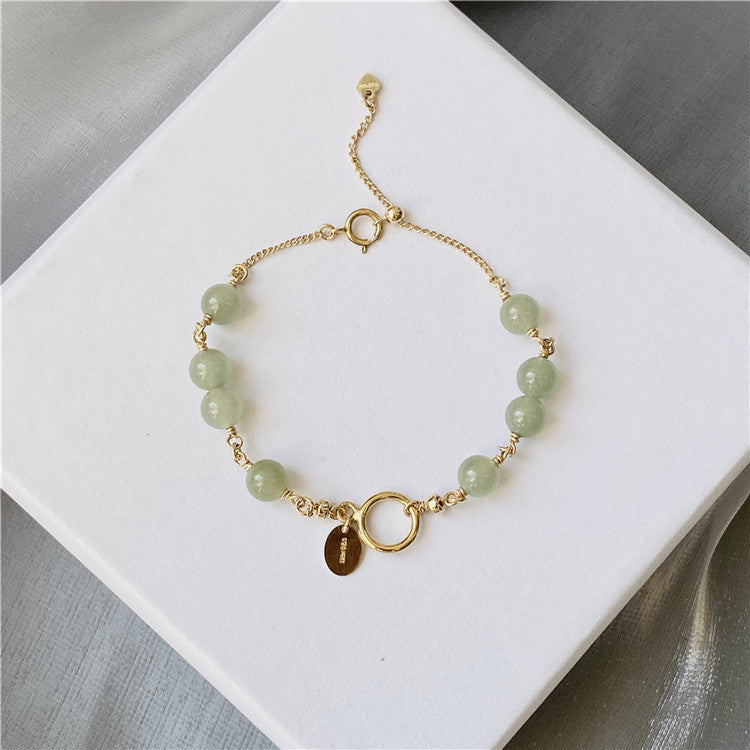 Close up of a Hetian jade beaded bracelet with gold filled chain and charms