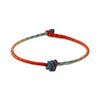 Close-up view of a red and blue hand-woven cord bracelet with a central knot detail
