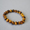 Close up of a brown and gold Tiger Eye beaded bracelet on a grey background