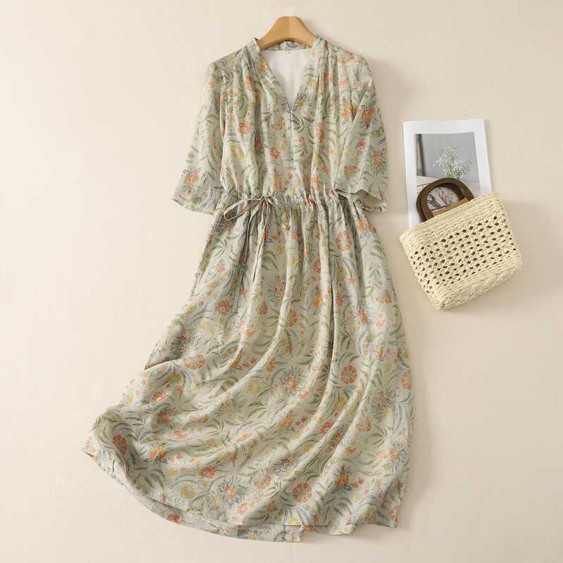 Long floral print dress hanging on a wooden hanger against a plain wall