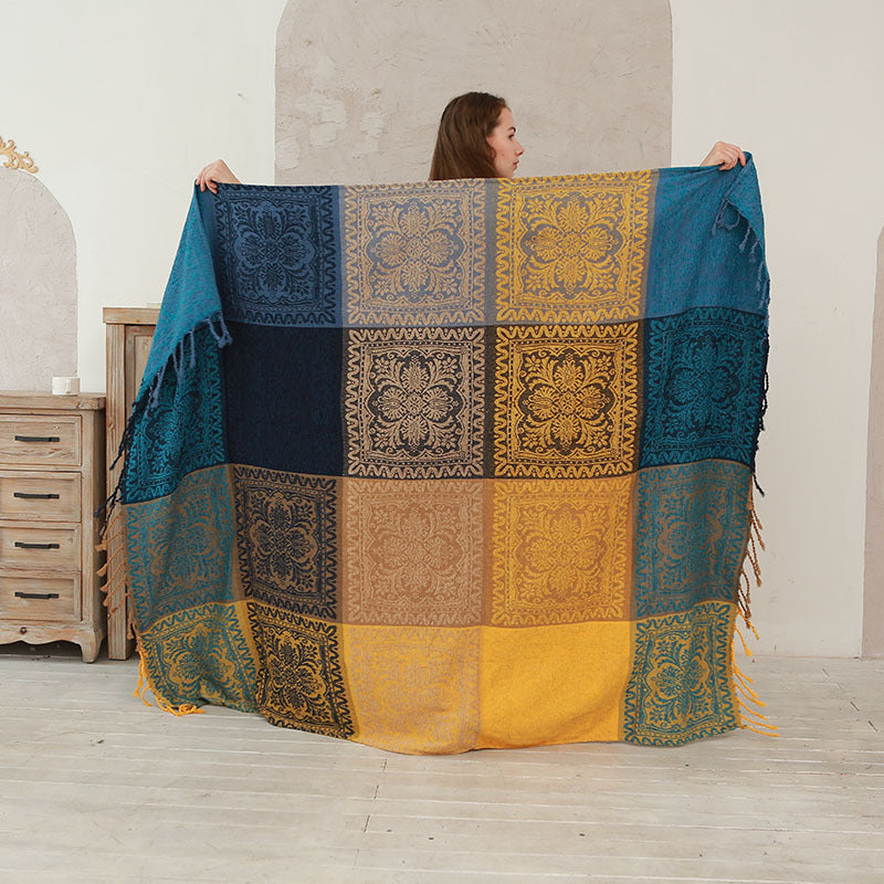 Woman holding up a blue and yellow patchwork chenille throw blanket with fringe