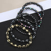 Several magnetic bracelets with geometric beads and links on a dark surface