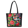 Black canvas tote bag with red embroidered peonies and a bird