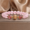 Pink crystal bracelet with strawberry quartz beads and a gold charm on a box