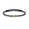 A black braided cord bracelet featuring a single small gold bead in the center.