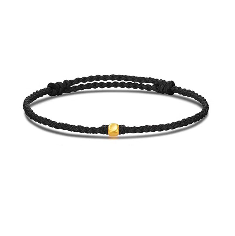 A black braided cord bracelet featuring a single small gold bead in the center.