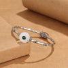 Silver tone copper bracelet with bamboo segments and a white peace buckle charm on a brown background