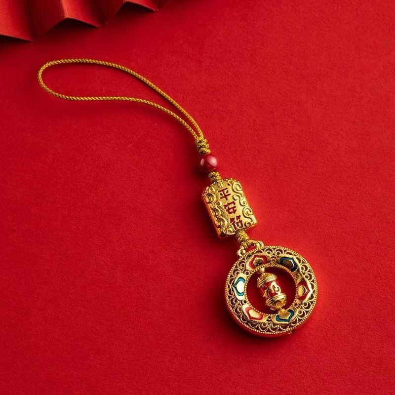 Gold-tone hanging charm with a Buddha figure and red bead against a red background