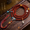 Coiled brown bodhi seed mala with turquoise and bone accents on wood