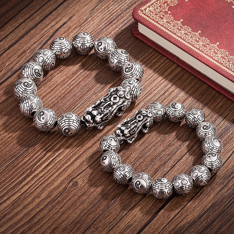 Close up of silver plated Pixiu bracelet with Bagua patterned beads on wood