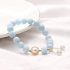 Light blue aquamarine bead bracelet with a central pearl charm on a white background