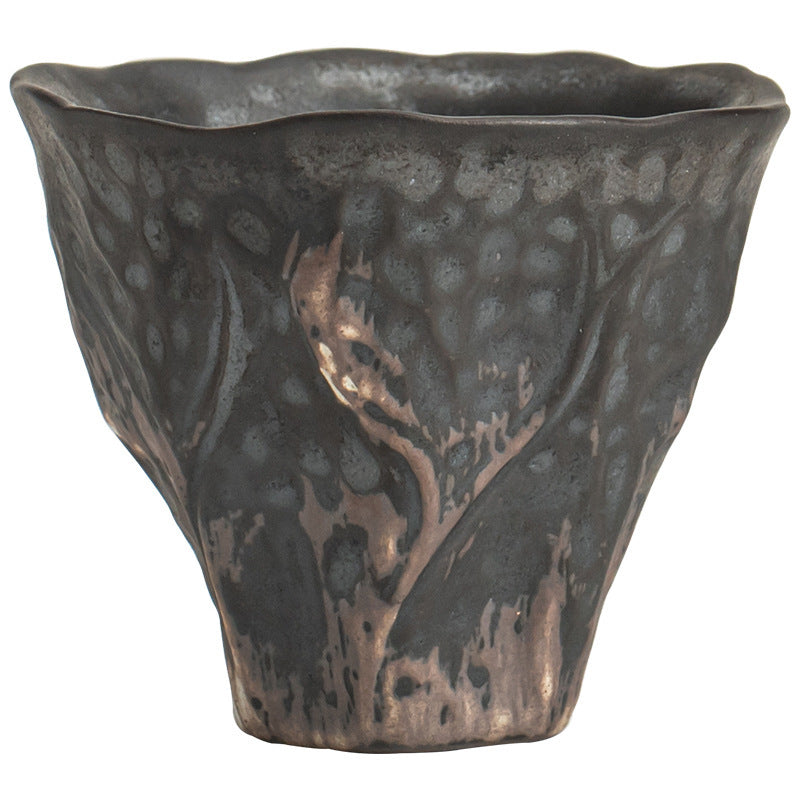 Close-up of a dark textured ceramic teacup with a lotus design