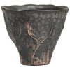 Close-up of a dark textured ceramic teacup with a lotus design
