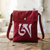 Red cotton crossbody bag with white embroidered Tibetan character on the front flap