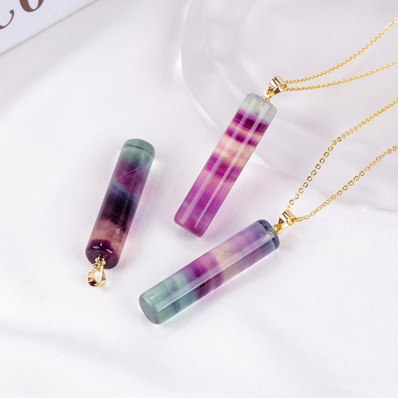 Three natural fluorite cylindrical pendants on gold chains displayed on a white surface