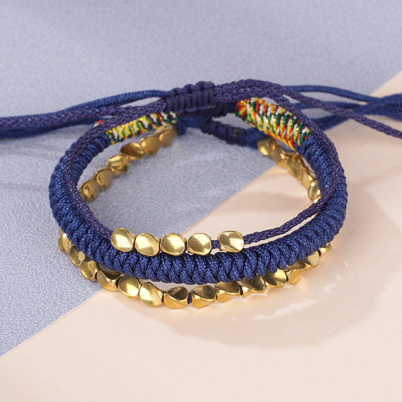 Three blue braided bracelets with gold copper beads stacked on a wrist