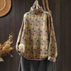 A mustard yellow knitted sweater with a floral pattern hanging on a wooden hanger