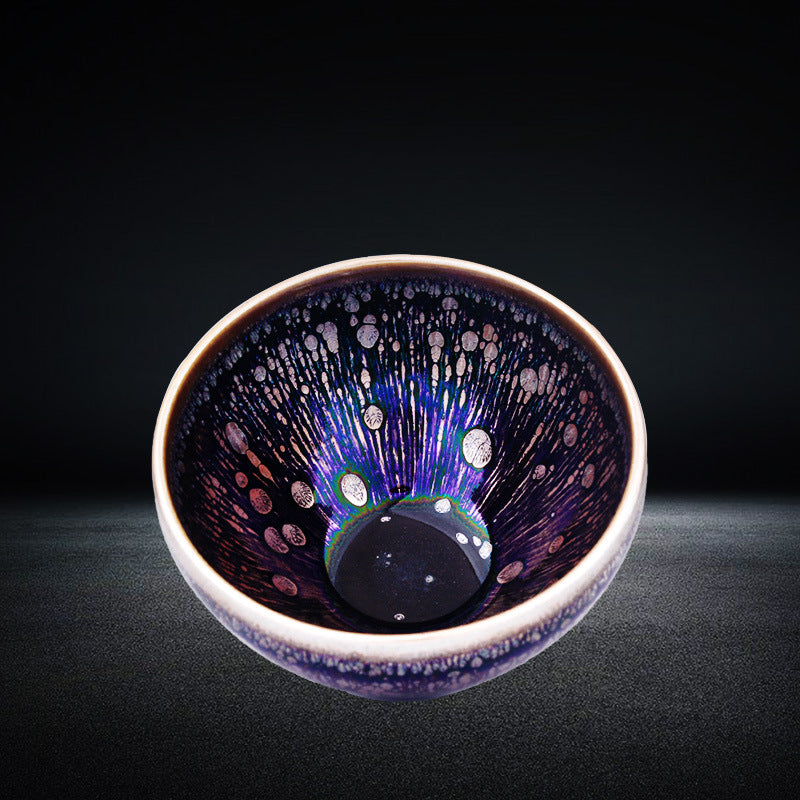 Close up view of a purple and black ceramic tea cup with silver speckles inside