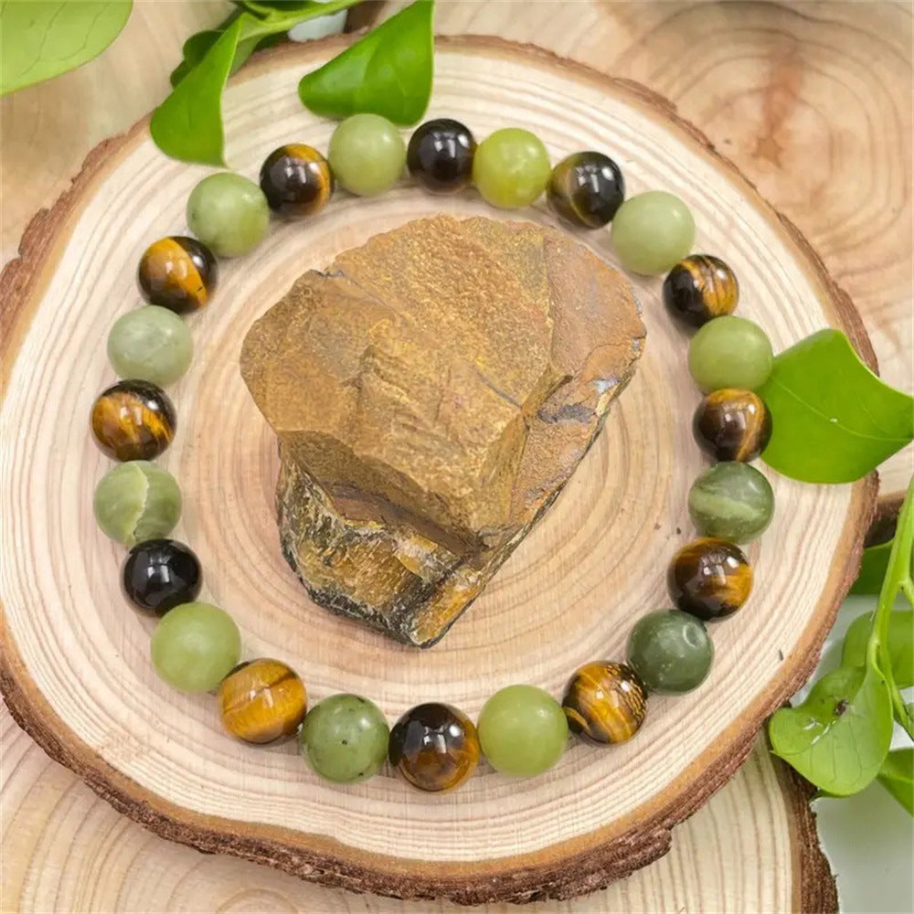 Round beaded bracelet with green jade and brown tiger eye stones on a wooden slice