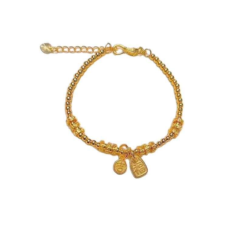 Gold-tone beaded bracelet with Ji and Fu charms resting on white display stones