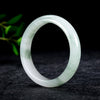 A translucent white and green Tianshan jade bangle bracelet standing upright