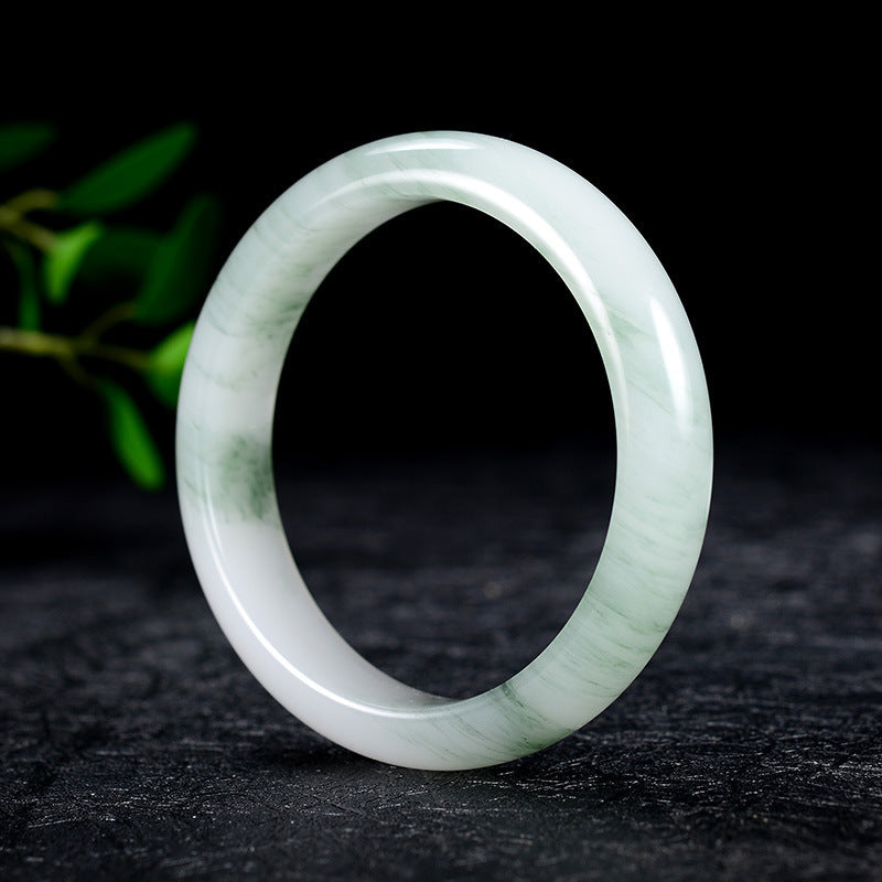 A translucent white and green Tianshan jade bangle bracelet standing upright