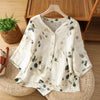 White cotton women's shirt with green plant print hanging on a wooden hanger