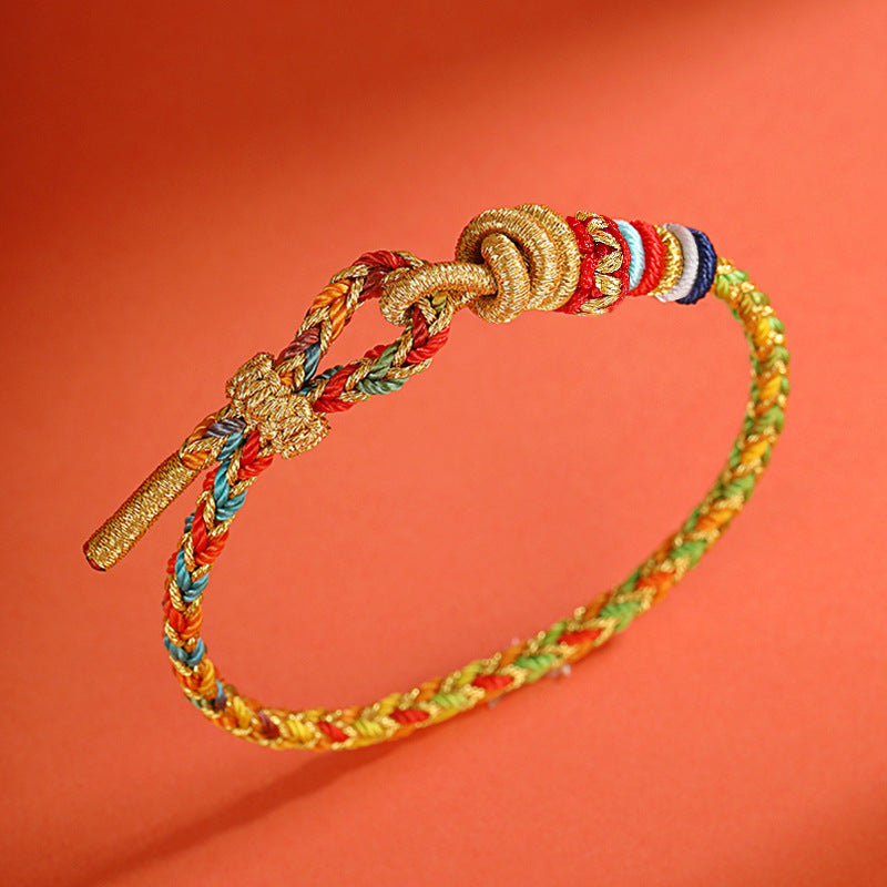 Close up of a multicolored braided rope bracelet with a gold dragon charm and knot closure